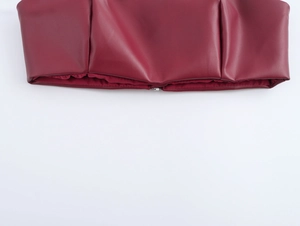 Détail d'un haut bustier en similicuir bordeaux avec texture lisse et fermeture éclair
