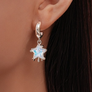 Close-up of a silver star earring with blue opal inlay worn on a model's ear