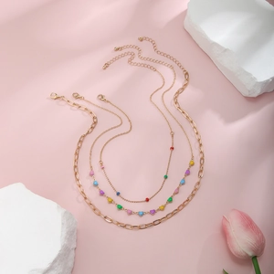 Layered gold necklace featuring colorful enamel heart pendants and tulip floral decor