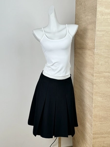Detail of a white camisole top paired with a black pleated skirt on a mannequin