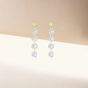 Macro shot of long gold earrings featuring five cascading round-cut clear crystal drops