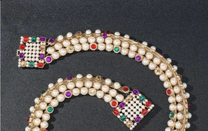 Detailed close-up of luxury gold chain belt with colorful rhinestones and pearls