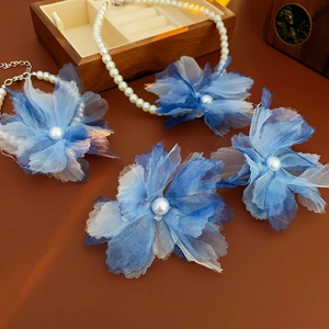 Detail of blue gradient mesh flower and pearl pendant necklace on a wooden box