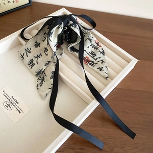 Detail of a Chinese style bow hair claw with calligraphy silk ribbons on a tray