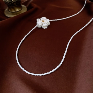 Close-up of white beaded camellia necklace on deep red silk for a vintage look