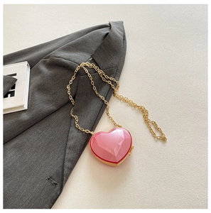 Detailed view of pink heart-shaped crossbody bag with geometric diamond facets and gold chain