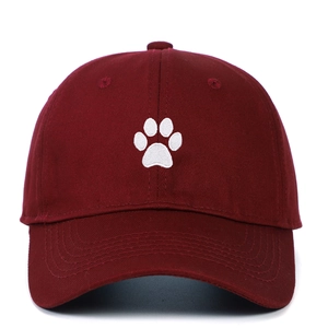 Close-up of a white paw embroidery on a burgundy cotton baseball cap with twill texture
