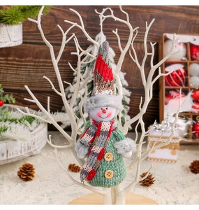 Detailed view of a knitted snowman ornament hanging on a white decorative branch