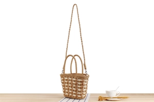 Detail of hand-woven straw bucket bag with dual handles and detachable shoulder strap