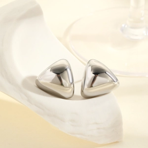 Macro shot of polished geometric triangle silver stud earrings on a textured stone base
