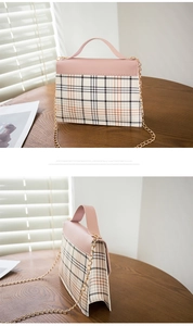 Detail of pink plaid mini flap bag with gold chain strap on a warm wooden tabletop