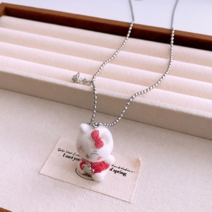 Detail of plush Hello Kitty pendant with metallic planet logo on a long silver ball chain