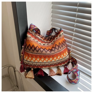 Detail of bohemian cross-body bag with ethnic embroidery patterns and colorful fringes