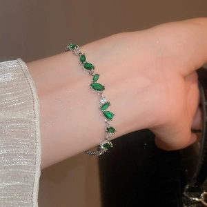 Détail macro du bracelet en argent avec zircons verts marquise au poignet d'une femme