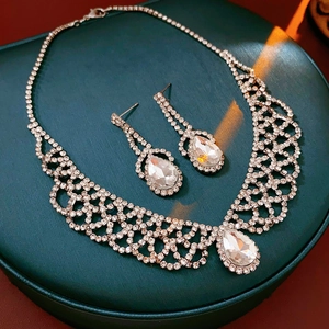 Macro view of silver teardrop jewelry set with clear crystals on a green stand