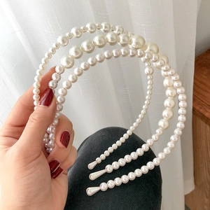 Detailed view of elegant white multi-layer pearl headband held by a hand