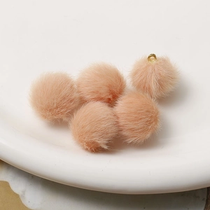 Detailed close-up of fluffy apricot and pink plush pompom pendants with gold loops