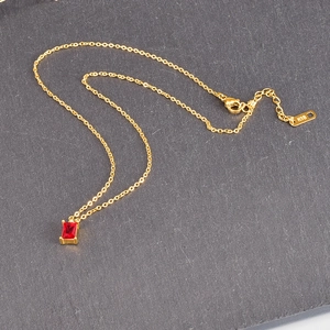 Detail of 18K gold plated necklace featuring a red rectangle gemstone and K18 tag