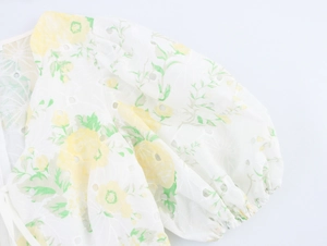 Detail of white dress with yellow floral embroidery, puff sleeves and hollow out lace
