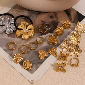 Flat lay of floral 18K gold and silver rings, earrings and hair ties on vintage background
