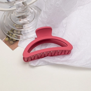 Detail shot of a large rose red matte hair claw clip on minimalist aesthetic background