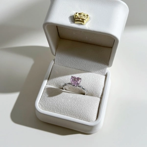Detailed top view of a pink heart-shaped crystal ring inside a white crown jewelry box