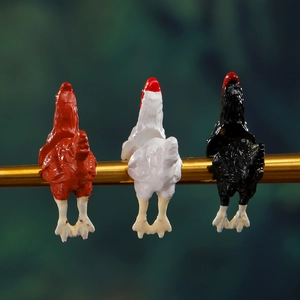 Tre orecchini pendenti a forma di gallo su barra dorata con sfondo di foresta