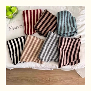 Close-up of premium wool blend striped scarves in various colors on a soft white bed sheet