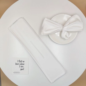 Close-up of white fabric hair bun maker with bow print detail on a ceramic plate