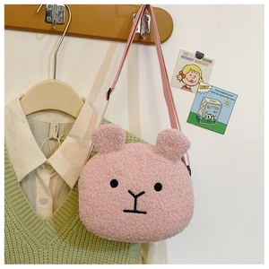 Pink plush teddy bear crossbody bag for kids hanging on a wooden hanger against a soft background