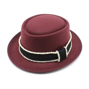 Detail of maroon wool pork pie hat featuring a black ribbon with delicate white beading