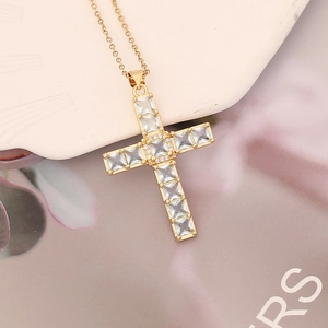 Macro shot of gold cross necklace with micro-paved cubic zirconia stones and shiny finish