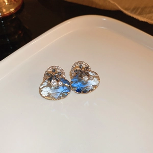 Détail macro de boucles d'oreilles fleur en cristal dégradé bleu avec finition dorée
