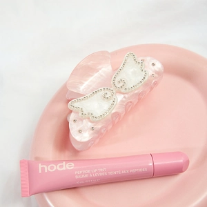 Haarklammer aus pinkem Acetat mit Schmetterling und Lipgloss auf einem Tablett