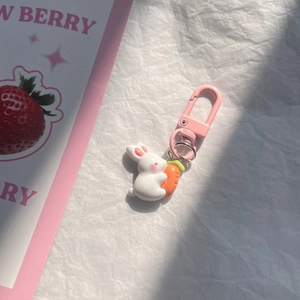Close-up of cute white bunny keychain with orange carrot and pink metal lobster clasp