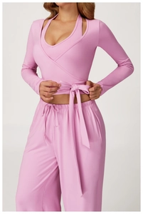 Close-up of pink long-sleeve wrap top with tie waist and ribbed knit texture detail