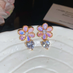 Close-up of purple resin flower earrings with heart-shaped zircon on a ceramic tray