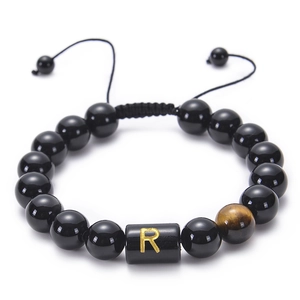 Close-up of handmade adjustable black agate bracelet featuring a golden R letter bead