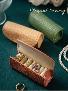 Dettaglio di astucci portagioie in pelle coccodrillo rosa, verde e beige con fessure