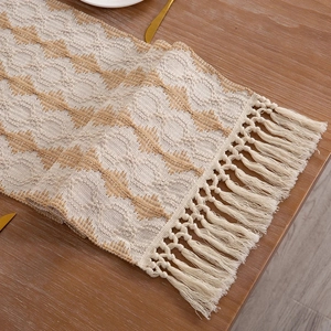 Detail view of woven cotton linen table runner with geometric textures and knotted tassels