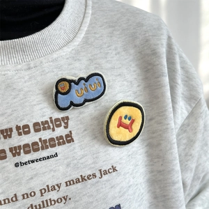 Close-up of cute cartoon embroidered badges featuring a blue cloud and yellow smiley face