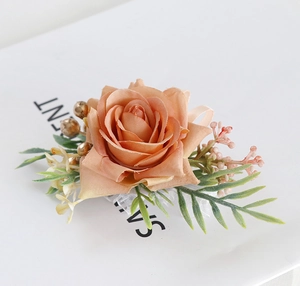 Macro detail of artificial apricot rose boutonniere with green leaves and lace