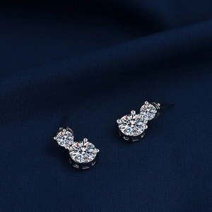 Macro shot of silver geometric earrings with double moissanite stones on blue fabric