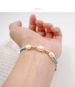 Detailed shot of handmade turquoise beads and freshwater pearl bracelet on a wrist