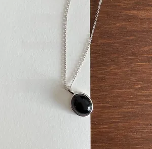 Macro shot of minimalist 925 silver necklace with an oval black gemstone pendant