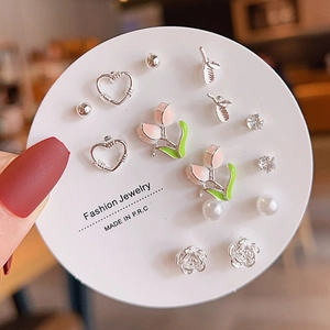 Close-up of heart, tulip, and pearl earring set displayed on a white round card