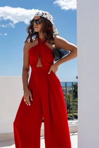Detailed fabric texture of a red halter neck wide-leg jumpsuit in outdoor sunlight