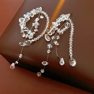Macro shot of sparkling faceted crystal drop tassel earrings on a premium leather box