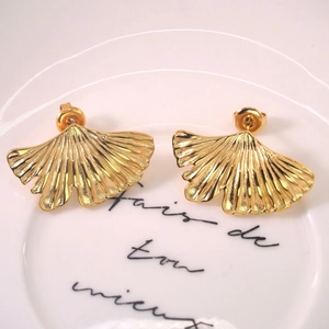Golden ginkgo leaf stud earrings in 14K gold plated stainless steel on white ceramic plate