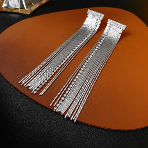 Detailed view of silver chain fringe earrings with sparkling rhinestone geometric base